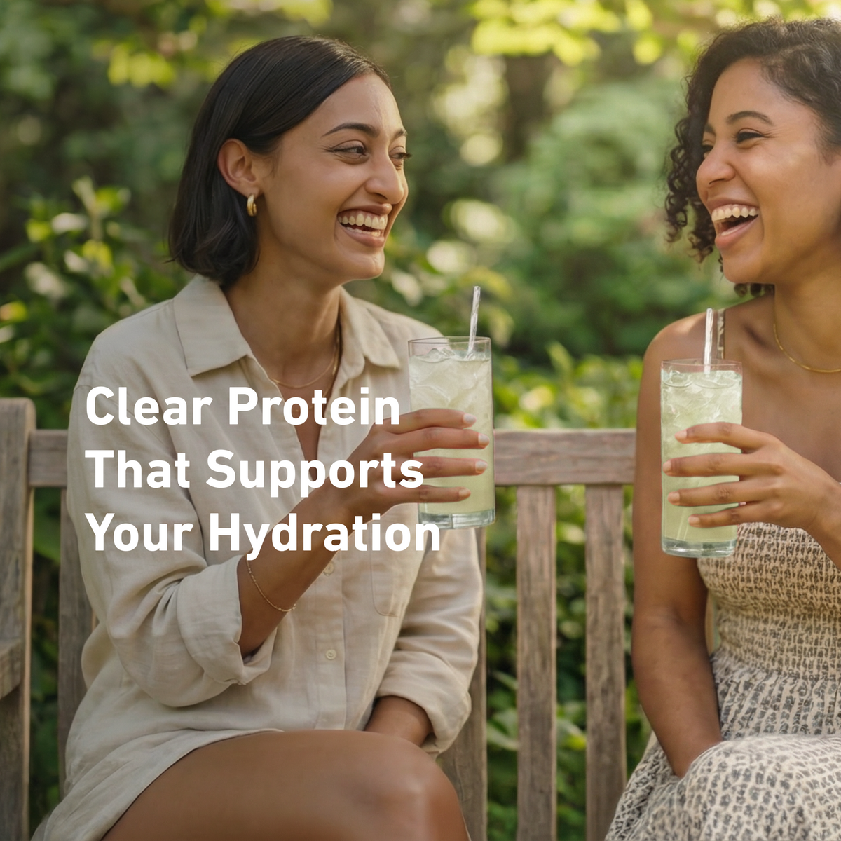 Two women laughing on a wooden bench outdoors, each holding a clear drink with a straw. Large white text across the left reads, 'Clear Protein That Supports Your Hydration.