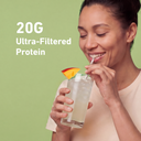 A woman drinking from a tall glass of iced beverage with a straw and a mango garnish, set against a solid light green background with the text '20G Ultra-Filtered Protein'.
