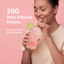 A woman in a beige top holds a pink protein drink with a lime garnish and a straw against a pink background, with text reading '20G Ultra-Filtered Protein' and 'Improved Taste & Better Mixability'.