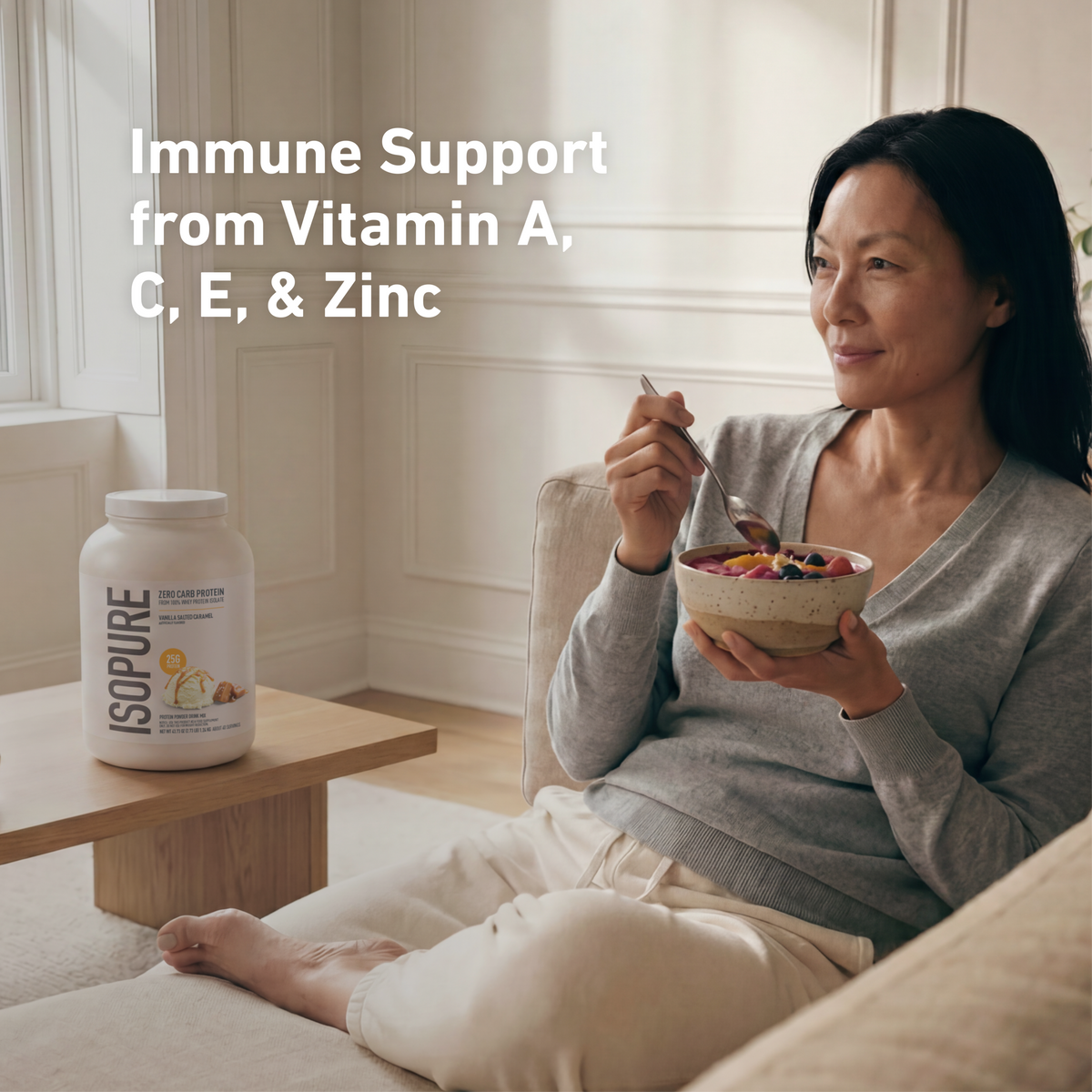 Woman eating a bowl of fruit with an ISOPURE protein powder container next to her, emphasizing immune support from vitamins and zinc.