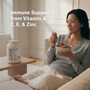 Woman eating a bowl of fruit with an ISOPURE protein powder container next to her, emphasizing immune support from vitamins and zinc.